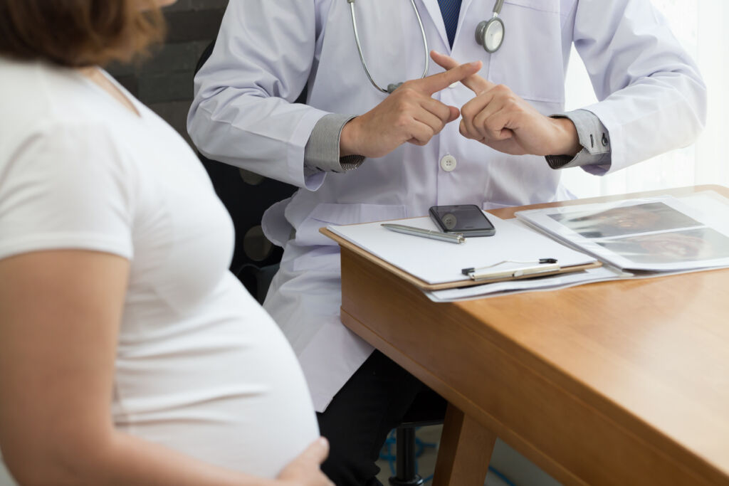 Doctor showing warning with hand sign and talking to the pregnant woman. Prohibition during pregnancy concept