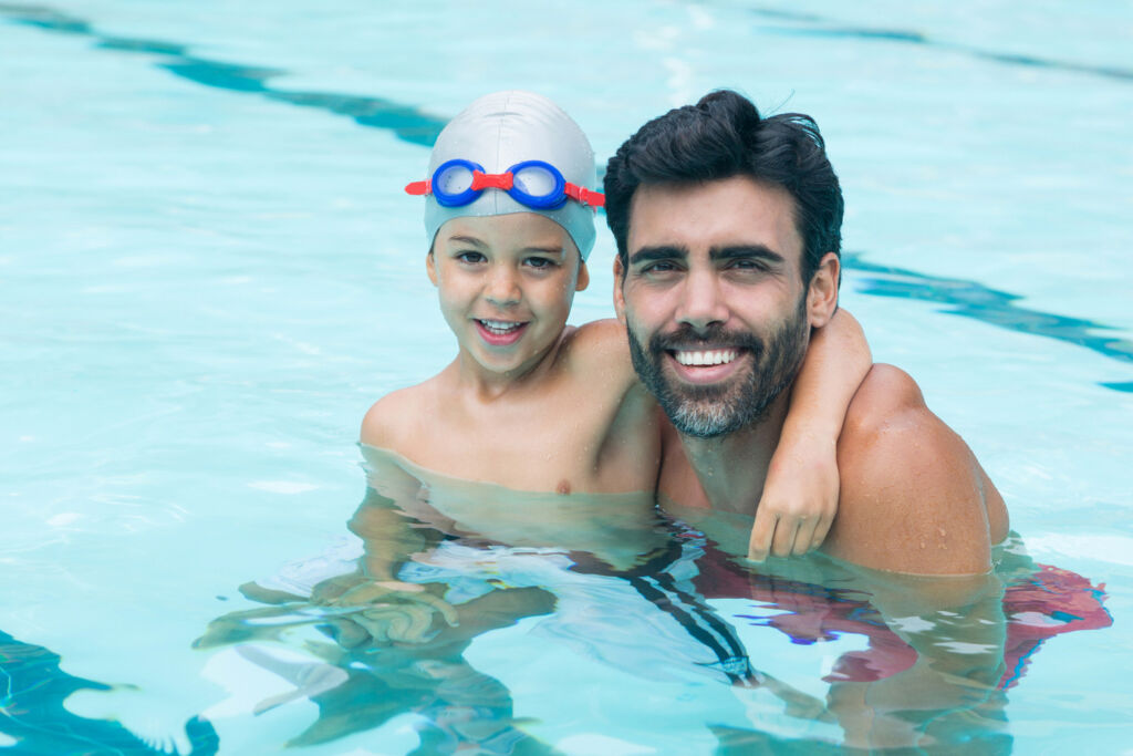 father and young boy playing in pool