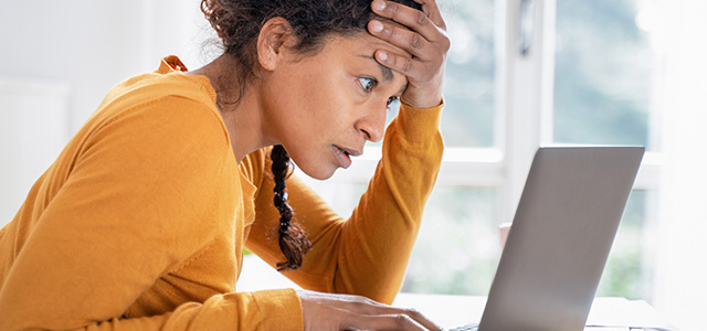 oung woman feeling stressed while looking bank account online